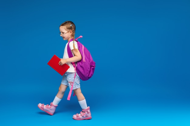 Petite fille avec un sac à dos et un livre