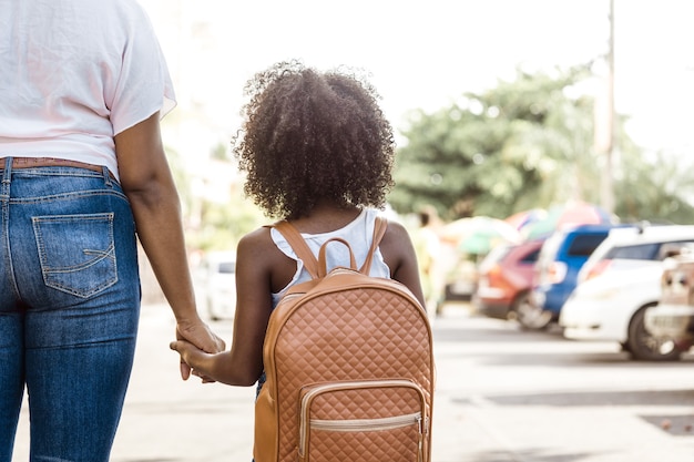 Photo petite fille avec sac à dos tient la main d'une personne. concept de retour à l'école.