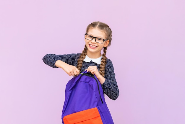 Une petite fille avec un sac d'école, un uniforme scolaire et de longues nattes va à l'école primaire à l'école et se prépare aux examens
