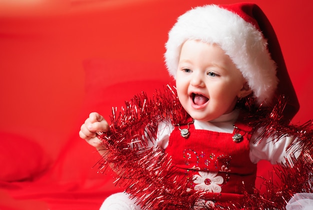 La petite fille de Santa regarde et s'asseyant sur le tissu rouge