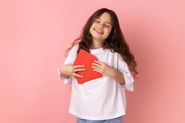 Petite fille satisfaite, debout, ouverte, enveloppe rouge, lecture, lettre romantique, être touchée