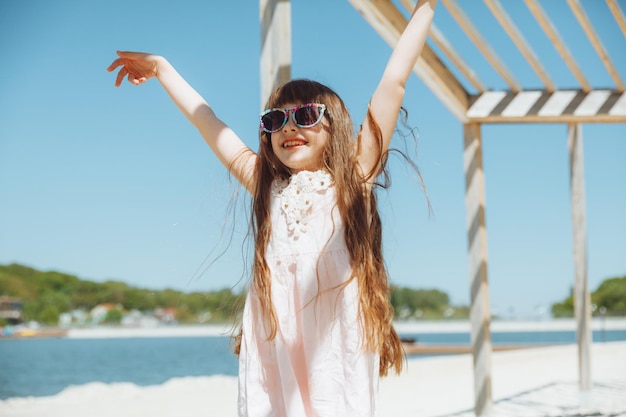 Petite fille sautant sur la plage au bord de la plage de la ville pendant les vacances d'été