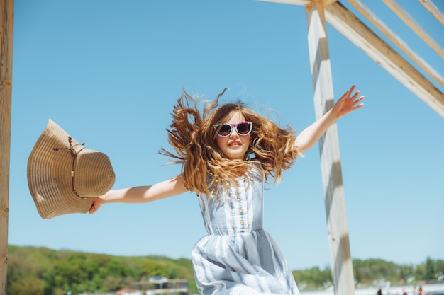 Petite fille sautant sur la plage au bord de la plage de la ville pendant les vacances d'été