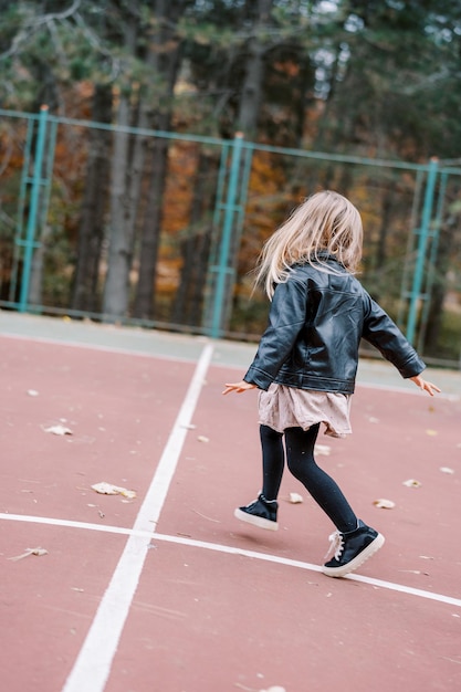 Photo une petite fille saute le long de l'aire de jeux en regardant vers l'arrière