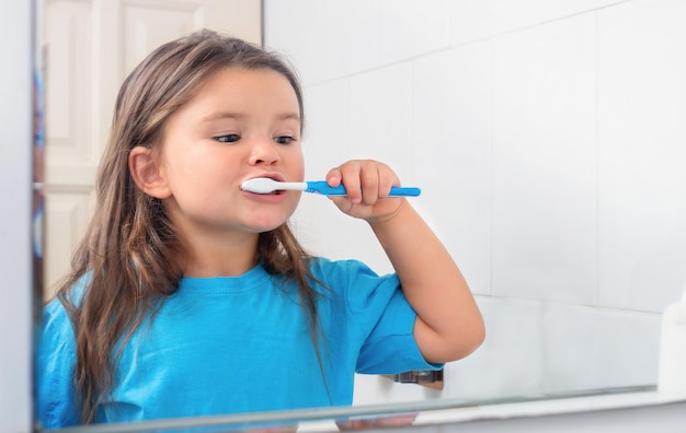 Petite fille se brosser les dents avec une brosse à dents dans la salle de bain