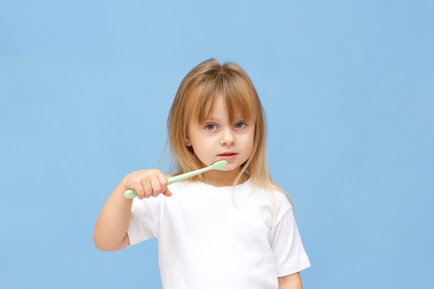 Petite fille se brosser les dents et porter sur fond bleu.