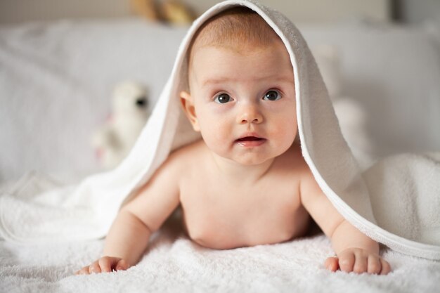 La petite fille se cache sous la couverture blanche - concept de parentalité ou d'amour