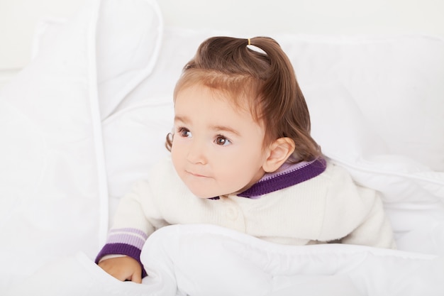 Petite fille se cache sous la couverture blanche