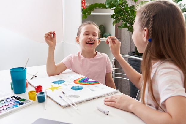 Petite fille se peindre le visage par une sœur aînée à la table