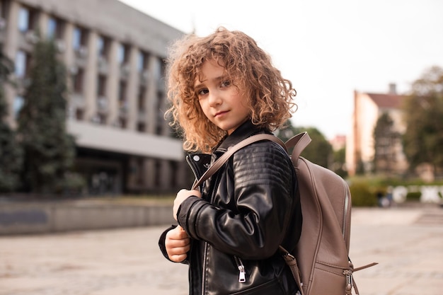 La petite fille se promène dans la ville avec un sac