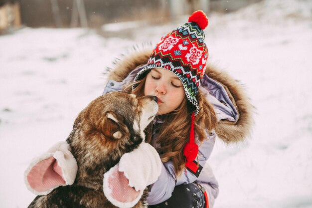 Une petite fille se promène avec son chien dans la forêt d'hiver.