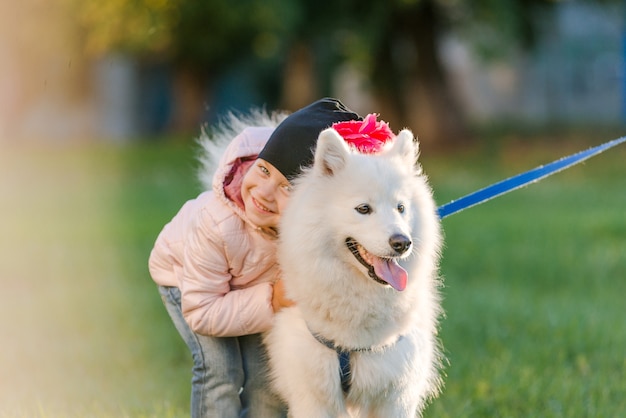 Petite fille se promène avec son chien Samoyède dans le parc en automne