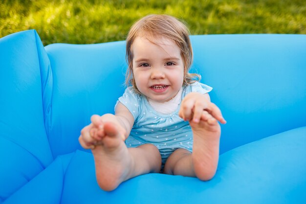 une petite fille se repose et joue au grand air. s'amuser sur un matelas gonflable bleu
