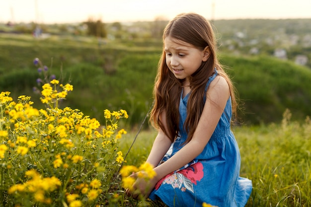 Petite fille sentant une fleur jaune