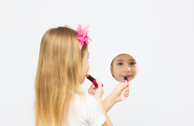 Petite fille de six ans essayant le rouge à lèvres de maman - apprendre à être une femme moderne