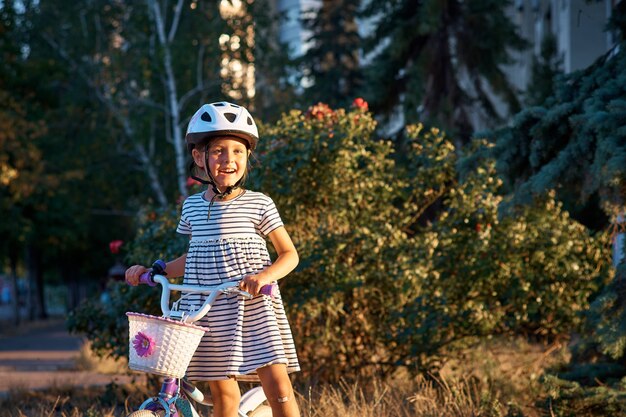 Petite fille avec son vélo dans le parc. Enfant sur le vélo