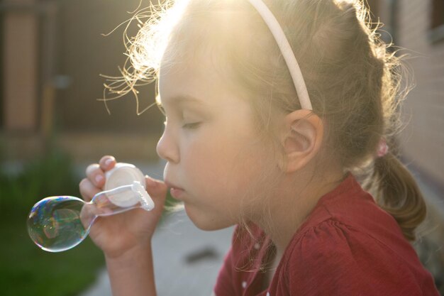 Une petite fille soufflant des bulles de savon dans le parc d'été