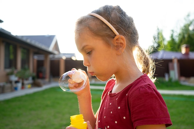 Une petite fille soufflant des bulles de savon dans le parc d'été
