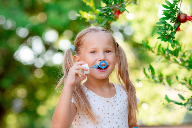 Une petite fille souffle des bulles de savon dans le parc