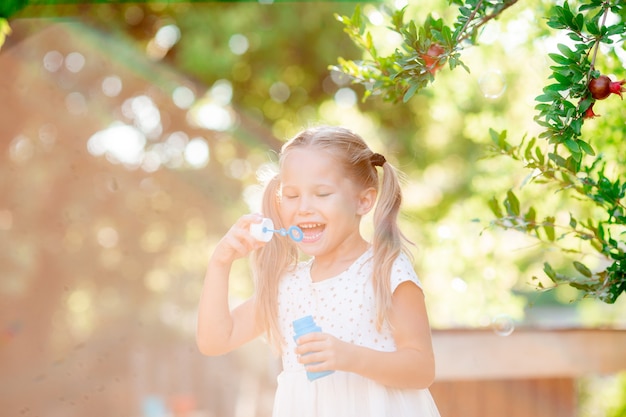 Une petite fille souffle des bulles de savon dans le parc