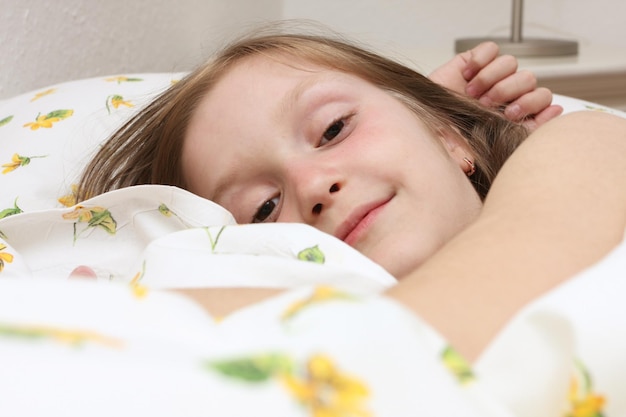 Petite fille souriante allongée sur le lit.