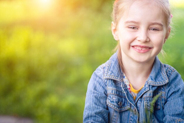 Petite fille souriante assise dans le champ d'herbe