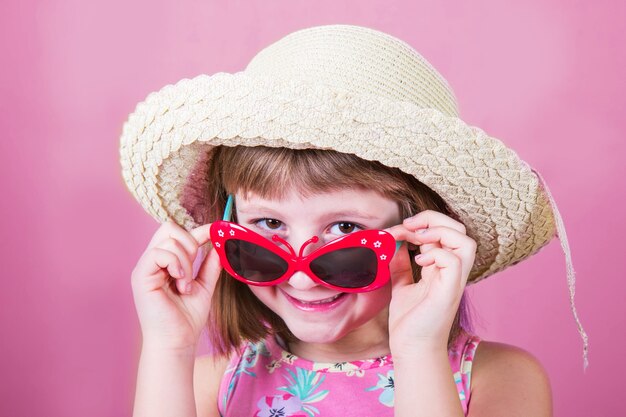 Petite fille souriante au chapeau de paille et lunettes de soleil