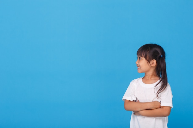 Petite fille souriante avec les bras croisés sur le mur bleu