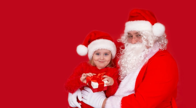 Petite fille souriante dans un chapeau avec le Père Noël et des cadeaux