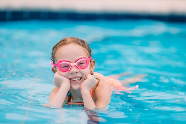 Petite fille souriante dans une piscine extérieure