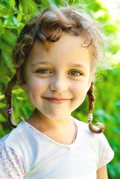 Petite fille souriante avec des feuilles vertes à l'extérieur