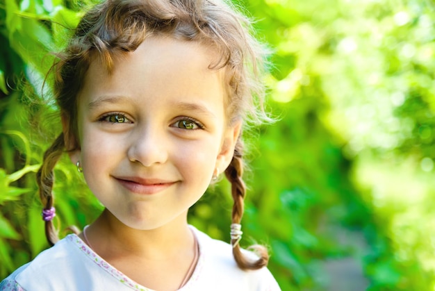 Petite fille souriante avec des feuilles vertes à l'extérieur
