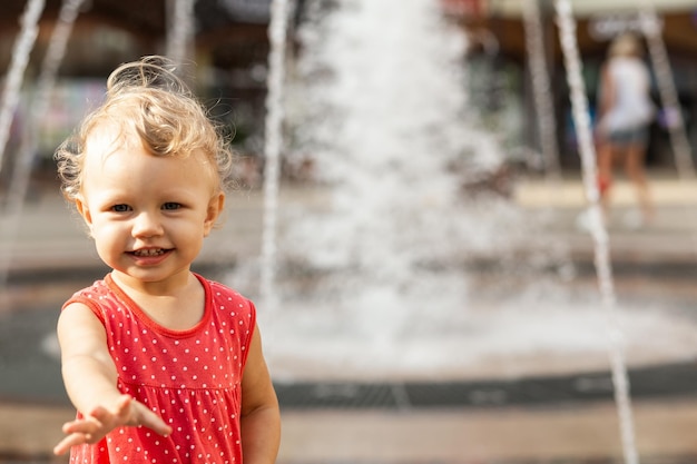 Petite fille souriante sur le fond d'une fontaine floue