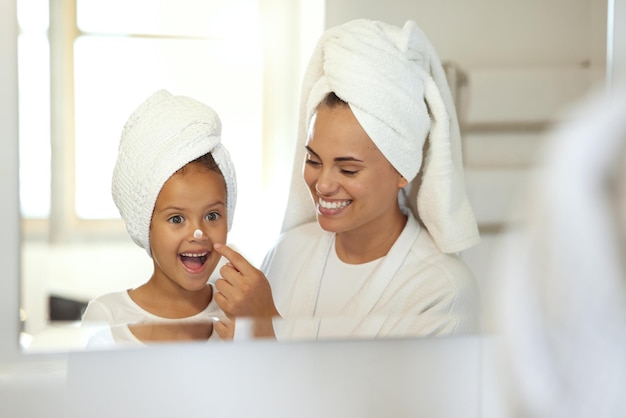 Petite fille souriante, joyeuse et excitée dans un spa avec sa mère Journée de soins personnels pour maman et fille mettant des crèmes et prenant soin de la peau