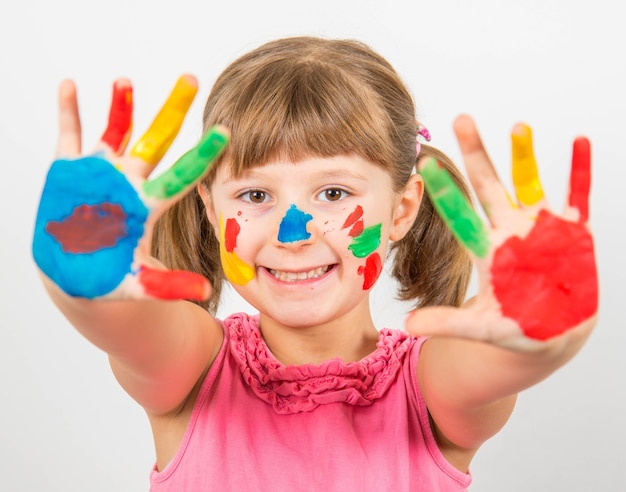 Petite fille souriante avec des mains peintes dans des peintures colorées