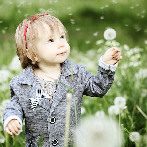 Petite fille souriante avec pissenlit sur l'herbe verte