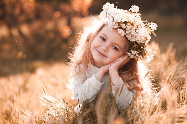 Petite fille souriante portant une couronne de fleurs à l'extérieur