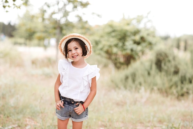 Petite fille souriante portant des vêtements d'été élégants et un chapeau de paille