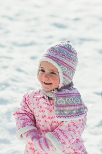 Petite fille souriante la première fois de ta vie marchant sur la neige