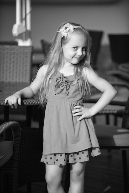 Petite fille souriante en robe bleue près de la table du café