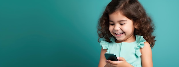 Petite fille souriante avec un téléphone portable sur fond coloré.