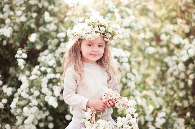 Petite fille souriante tenant un panier avec des fleurs à l'extérieur