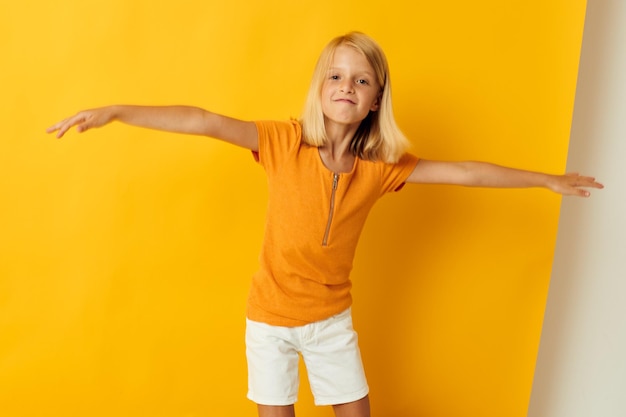 Petite fille sourire gestes de la main posant des vêtements décontractés fun fond jaune inchangé