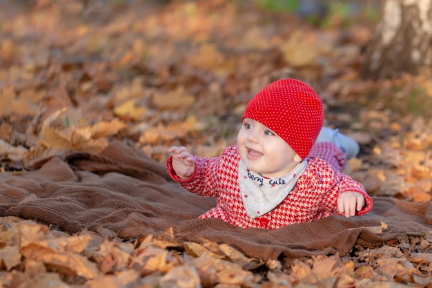 La petite fille sourit joyeusement allongée sur un tapis doux par une chaude journée d'automne