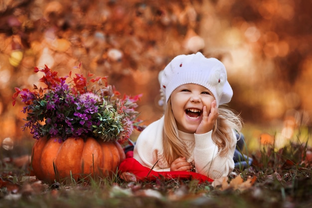 petite fille sourit et se couche sur les feuilles d'automne