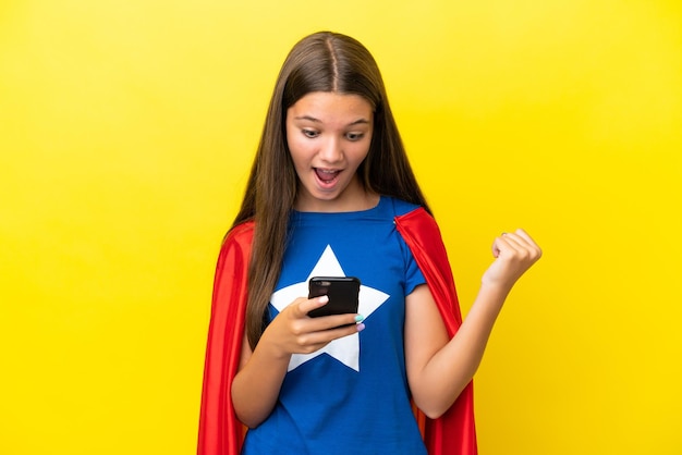 Petite fille de super-héros caucasienne isolée sur fond jaune surprise et envoyant un message