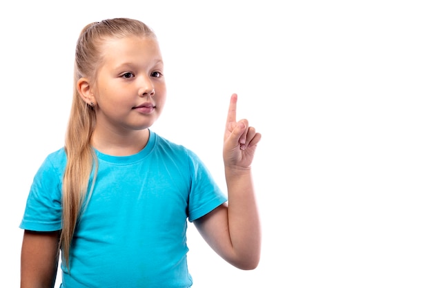 Une petite fille en T-shirt bleu leva son index. Isolé sur fond blanc. Place pour votre texte.