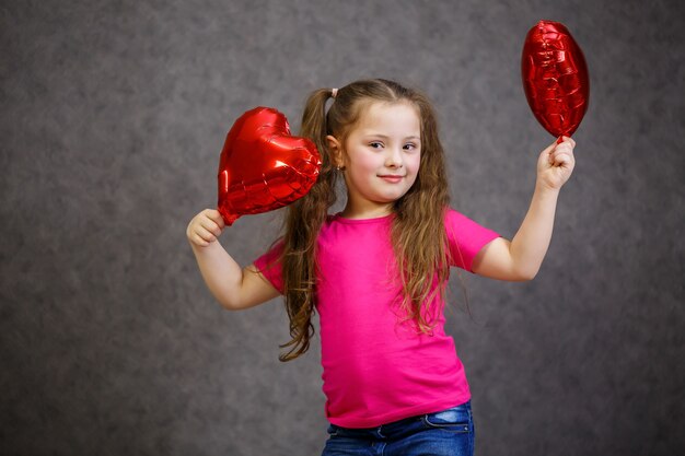 Petite fille en T-shirt rose joue avec des ballons