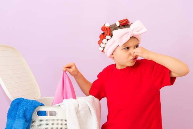 Une petite fille en T-shirt rouge et avec des bigoudis sur la tête n'aime vraiment pas les vêtements sales.