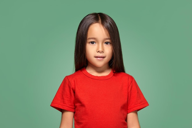 Petite fille en t-shirt rouge sourit en t-shirt rouge fond vert